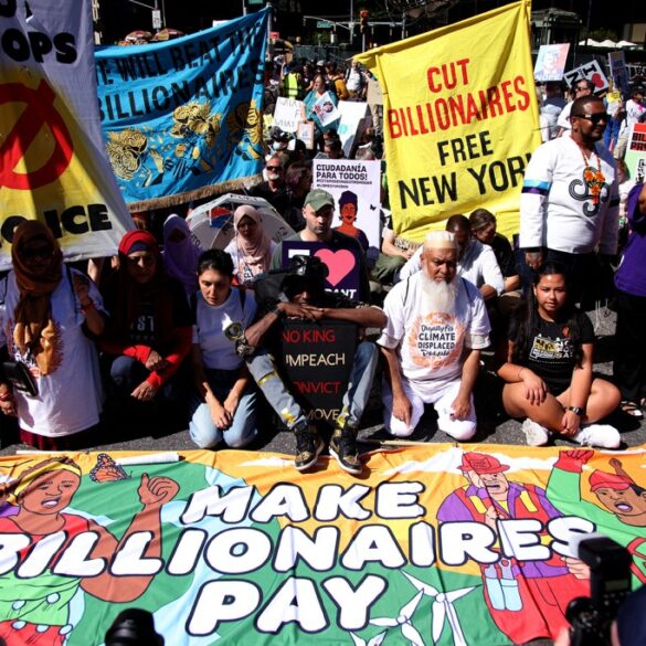 People protesting with signs and banners reading "Cut Billionaires Free New York," "No Troops No War Noice," "Defend Earth," and "Make Billionaires Pay."
