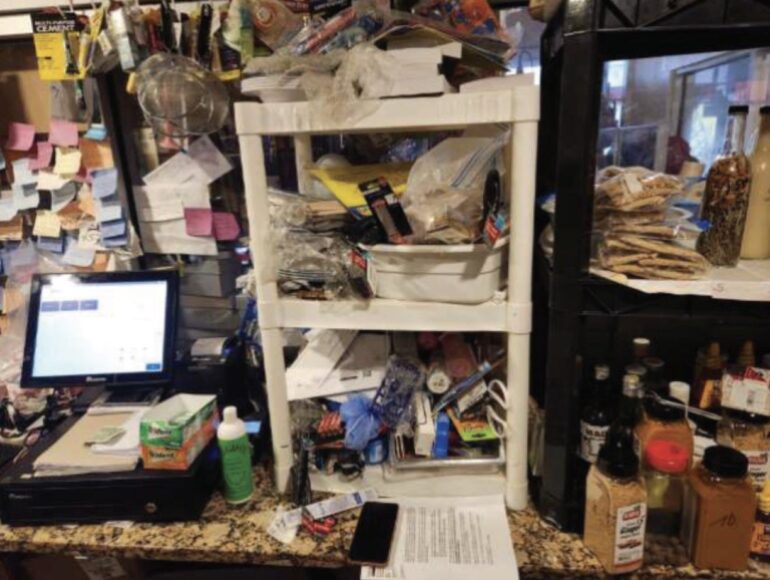 Cluttered checkout area featuring a computer, shelves filled with assorted items, and numerous sticky notes on the wall.