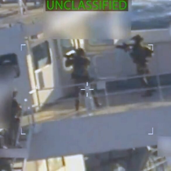 A video still showing soldiers with rifles on a boat, with the word "UNCLASSIFIED" at the top.