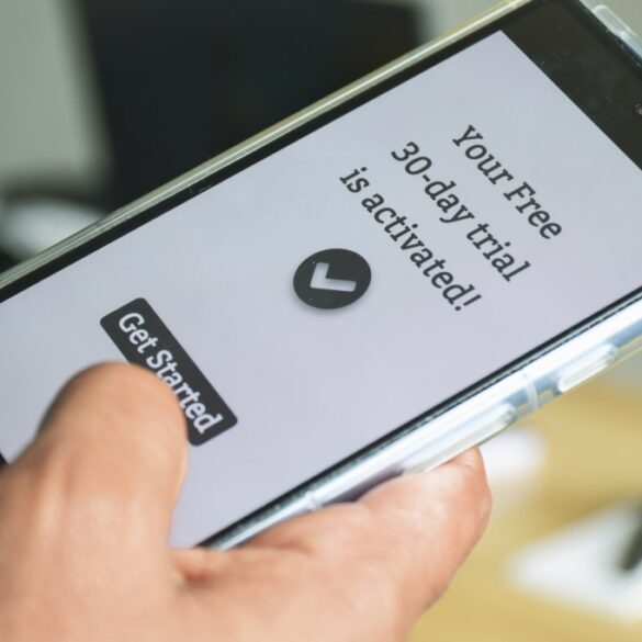 Hand holding a smartphone with "Your Free 30-day trial is activated!" and a "Get Started" button on the screen.