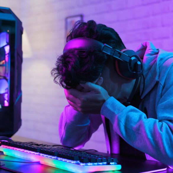 Upset PC gamer with head in hands by his PC