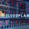 The Cloudflare logo on a window with many red and green lava lamps inside.