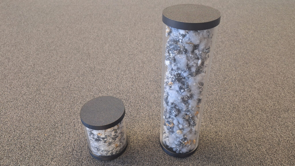 Tiny canister of compressed dirt, next to a larger one showing the same amount of dirt, but without any compression