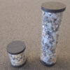Tiny canister of compressed dirt, next to a larger one showing the same amount of dirt, but without any compression