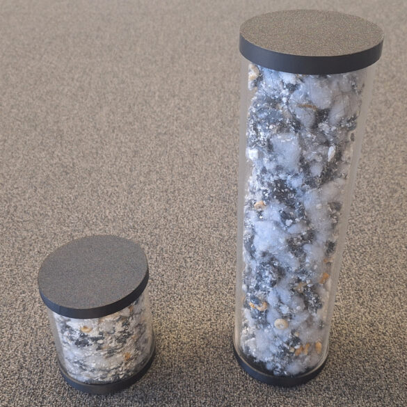 Tiny canister of compressed dirt, next to a larger one showing the same amount of dirt, but without any compression