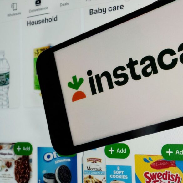 An Instacart webpage is shown on a phone with an Instacart logo and various products such as drinks and snacks visible in the background.