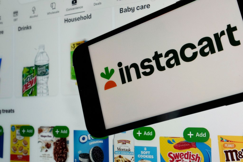 An Instacart webpage is shown on a phone with an Instacart logo and various products such as drinks and snacks visible in the background.