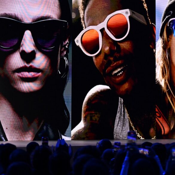 Mark Zuckerberg on stage with large images of people wearing smart glasses behind him.