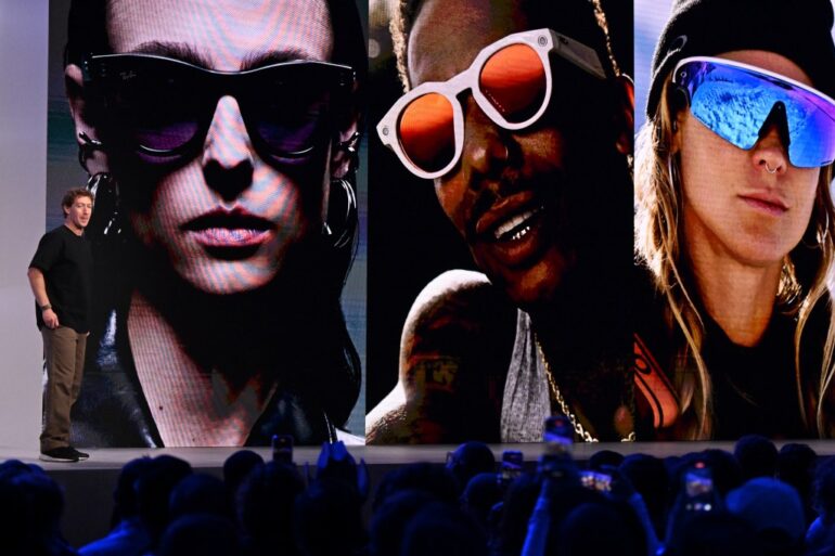 Mark Zuckerberg on stage with large images of people wearing smart glasses behind him.