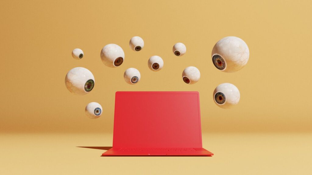 Conceptual image with a bunch of floating eyeballs in different sizes overlooking a red computer, could symbolize ideas around malware and computer viruses