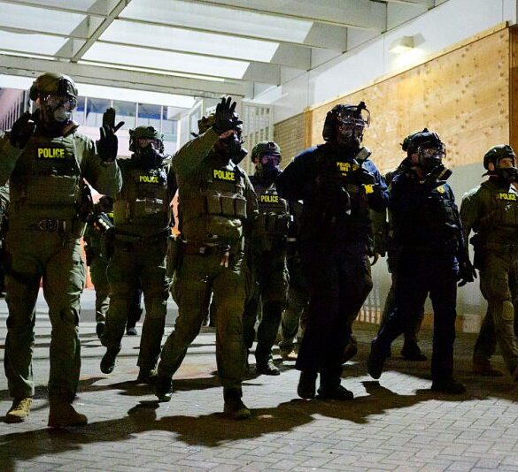 Federal agents keep protestors back from an Immigration and Customs Enforcement (ICE) facility in downtown Portland, Oregon, on October 6, 2025. President Donald Trump threatened on October 6, 2025, to use emergency powers against rebellion to deploy more troops into Democratic-led US cities, intensifying his rhetoric as his attempts to mobilize the military face legal challenges. Trump openly mulled use of the Insurrection Act after a federal judge in Oregon temporarily halted a National Guard deployment in Portland, while another judge in Illinois allowed a similar move to proceed for now in Chicago. (Photo by Mathieu Lewis-Rolland / AFP) (Photo by MATHIEU LEWIS-ROLLAND/AFP via Getty Images)