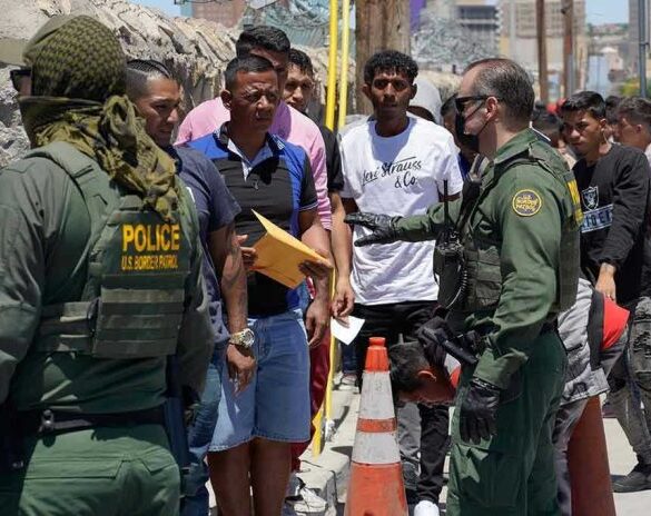 Border patrol agents inspecting group of individuals in line.