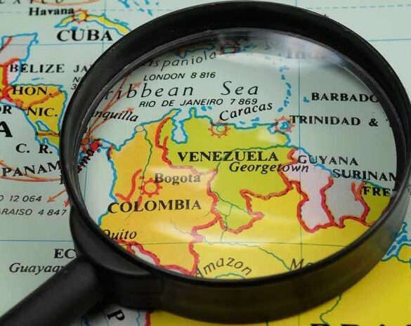 Magnifying glass focusing on Venezuela and Colombia on map.