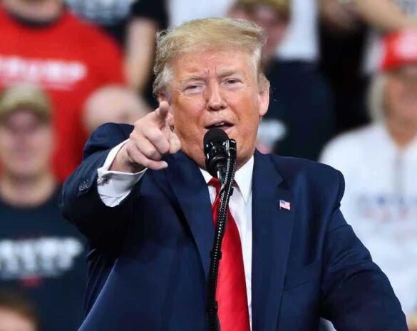 Man in suit pointing, speaking at a rally.