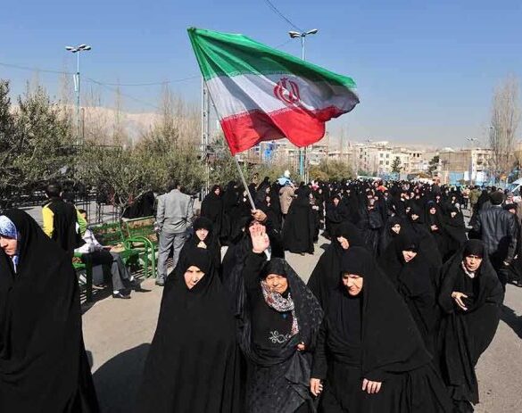 Group of women in black attire marching with an Iranian flag