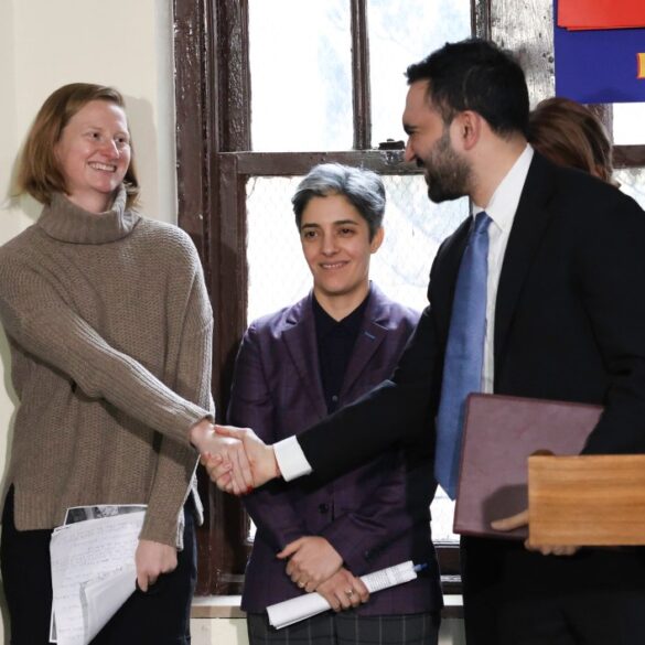 Zohran Mamdani and Cea Weaver shaking hands, with a woman in a purple jacket smiling between them.