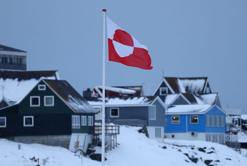 NUUK, GREENLAND - JANUARY 17: The Greenlandic flag flies over houses on January 17, 2026 in Nuuk, Greenland. Greenlandic, Danish and other European leaders are hoping they can still avert an intervention by the United States to forcefully acquire the island as U.S. President Donald Trump continues to insist the U.S. must have Greenland, suggesting even by military means if necessary. (Photo by Sean Gallup/Getty Images)