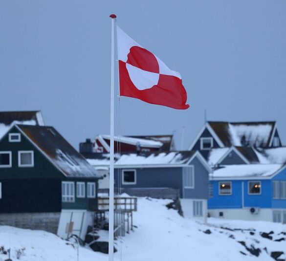 NUUK, GREENLAND - JANUARY 17: The Greenlandic flag flies over houses on January 17, 2026 in Nuuk, Greenland. Greenlandic, Danish and other European leaders are hoping they can still avert an intervention by the United States to forcefully acquire the island as U.S. President Donald Trump continues to insist the U.S. must have Greenland, suggesting even by military means if necessary. (Photo by Sean Gallup/Getty Images)