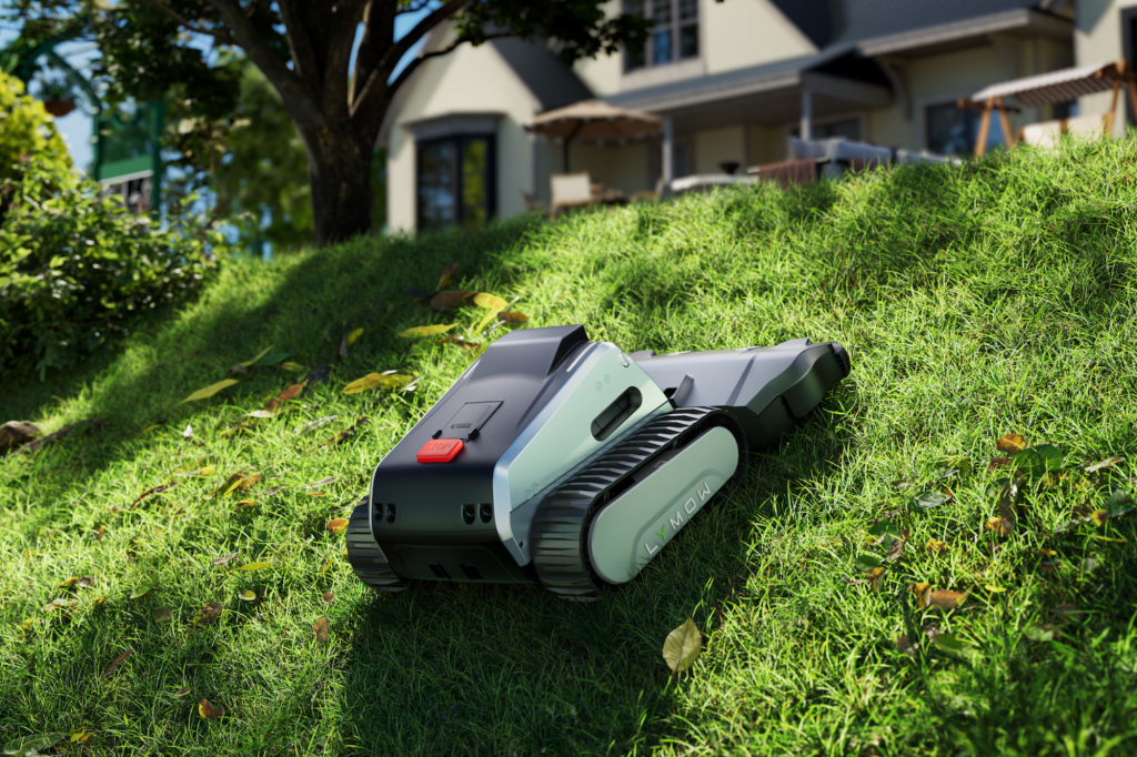 Illustration of a robotic lawn mower with tracks on a grassy hill with a house in the background.