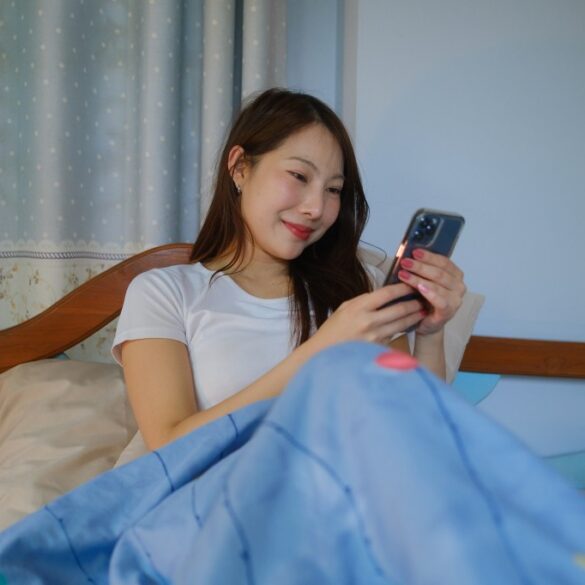 Woman on phone in bed.
