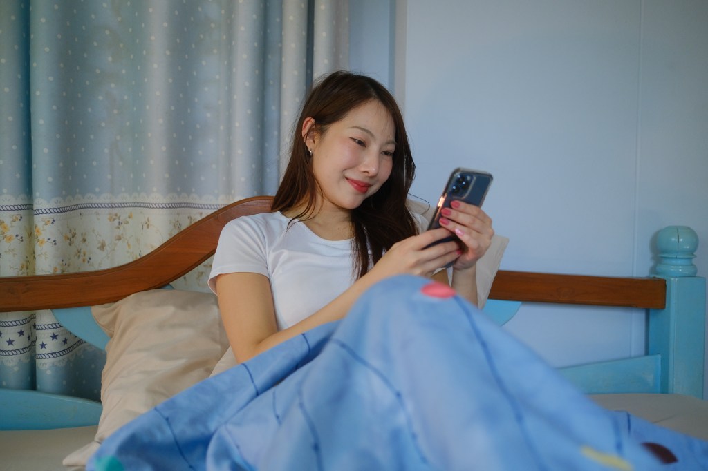 Woman on phone in bed.