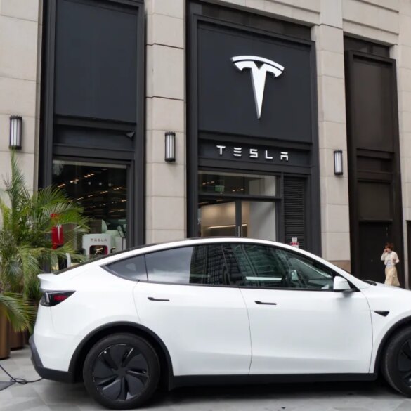 A white Tesla car charging outside a Tesla store in Shanghai, China.