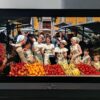 A shot of Maria and the Von Trapp children at a fruit stall at a market from The Sound of Music 4K Blu-ray on LG G5