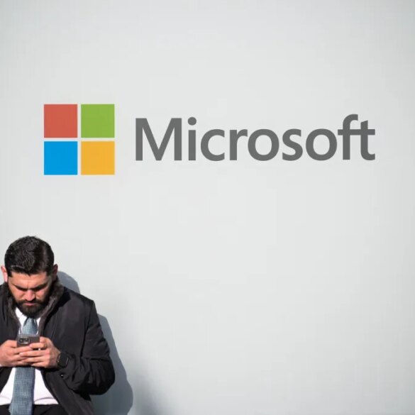 A man looking at his phone next to a Microsoft logo at the World Economic Forum.