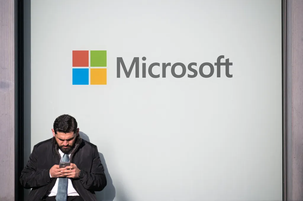 A man looking at his phone next to a Microsoft logo at the World Economic Forum.