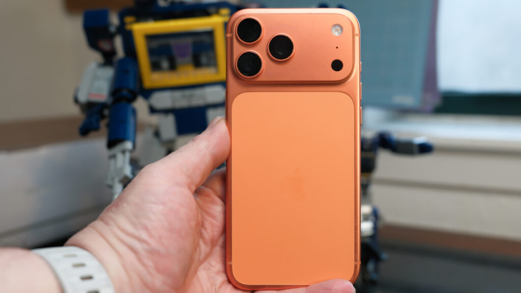 Apple iPhone 16 Pro Max in orange showing various Apple Messages features including sending check-ins, Apple Cash, and doodles