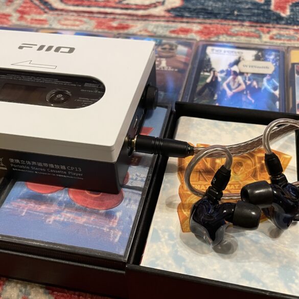 FiiO's CP13 with Campfire Audio Clara IEMs, on top of several cassette tapes, all on a colorful carpet