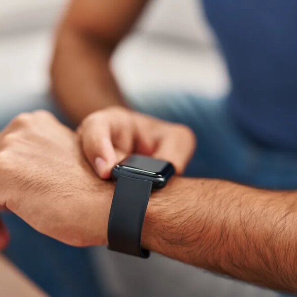 Young Hispanic man operating a smartwatch on his wrist.