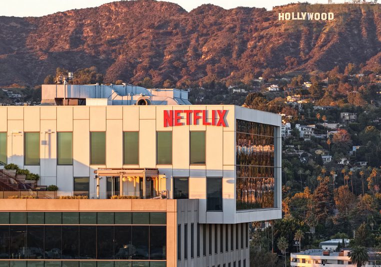 LOS ANGELES, CALIFORNIA - DECEMBER 05: An aerial view of the Netflix logo displayed at Netflix studios, with the Hollywood sign in the distance, on December 5, 2025 in Los Angeles, California. Netflix and Warner Bros. Discovery, Inc. have announced an $82.7 billion deal for Netflix to acquire Warner Bros. film and TV studios, HBO Max, and HBO. (Photo by Mario Tama/Getty Images)