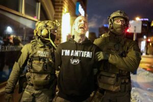 Federal agents with Homeland Security Investigations (HSI) detain a protestor wearing an "Antifa" shirt outside a residential building in Minneapolis, Minnesota, on February 5, 2026. US President Donald Trump suggested on February 4 that a "softer touch" may be needed on immigration, as his administration said 700 federal officers would be pulled from Minnesota but that mass deportations would not stop. The fatal shootings of two protesters by federal officers in Minneapolis last month sparked widespread outrage in the United States and calls for an end to immigration raids in the Midwestern city, but Trump's administration has been reluctant to shift course. (Photo by Charly TRIBALLEAU / AFP via Getty Images)