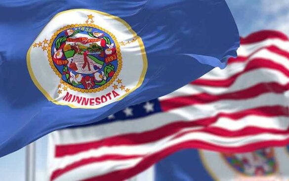 Minnesota state flag with American flag in background.