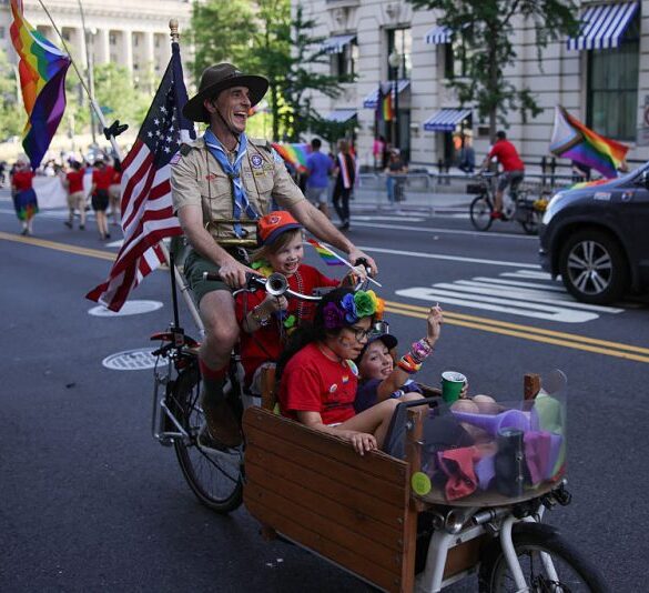 A person representing Scouting America rides a bicycle with children during the WorldPride 2025 parade in support of LGBTQ+ rights in Washington, D.C. on June 7, 2025. (Photo by Bryan Dozier / Middle East Images via AFP) (Photo by BRYAN DOZIER/Middle East Images/AFP via Getty Images)