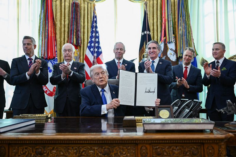 US President Donald Trump holds up a signed executive order in the Oval Office in the White House in Washington, DC, on January 30, 2026. Also pictured, US Transportation Secretary Sean Duffy (L), Roger Penske, chair of the Penske Corporation (2L) and US Interior Secretary Doug Burgum (3R). (Photo by Annabelle GORDON / AFP via Getty Images)