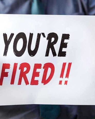 Person holding YOURE FIRED sign.