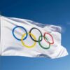 Olympic flag waving against clear blue sky.
