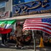 A man walks by a Iranian Market with an Iranian and an American flag outsite the shop in the Persian Square at the West LA neighborhood with in Los Angeles, California on February 28, 2026. The US and Israel launched an attack of unprecedented scale against Iran on Saturday, reportedly killing more than 200 people, with Tehran launching a retaliatory missile barrage that sent people running for cover across the Middle East. (Photo by Apu GOMES / AFP via Getty Images)