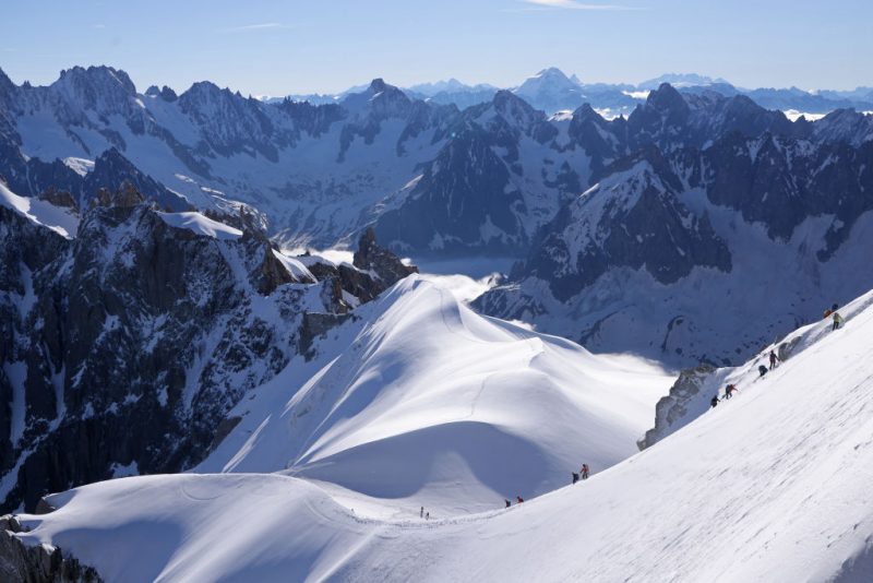 CHAMONIX-MONT-BLANC, FRANCE - JULY 02: Alpinists descend along a narrow ridge of ice and snow from the Aiguille Du Midi peak at 3,800 meters towards the Col du Midi basin in the Mont Blanc massif mountain range on July 02, 2024 near Chamonix-Mont-Blanc, France. The Col du Midi is part of the accumulation zone that contributes ice to the Mer de Glace, Europe's fourth biggest glacier and 12km long. The Mer de Glace, like nearly all of Europe's glaciers, is melting fast. According to glaciologists the Mer de Glace lost 800 meters in length between 1993 and 2018, as well as 120 meters in depth at its lower region. While Europe's glaciers have been steadily receding since the Little Ice Age that ended in the mid 19th-century, periods of intermittent glacier growth extended into the 1980s. Since then the glaciers have been receding rapidly, with the pace of melting accelerating sharply in the last decade. Scientists blame global warming, which is extending and intensifying the summer melting season of the glaciers. Diminished annual snowfalls are leaving the glaciers more exposed to the sun and preventing the formation of new ice. (Photo by Sean Gallup/Getty Images)