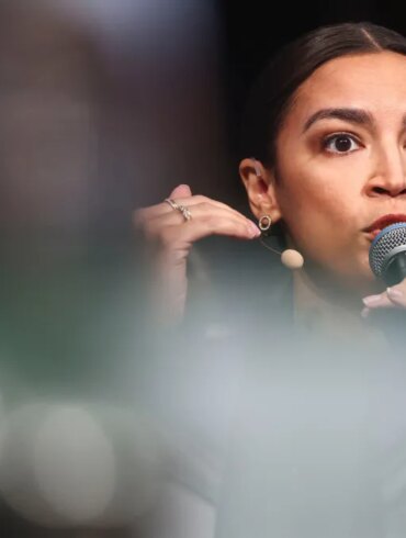 U.S. Representative Alexandria Ocasio-Cortez speaking into a microphone at the Munich Security Conference.
