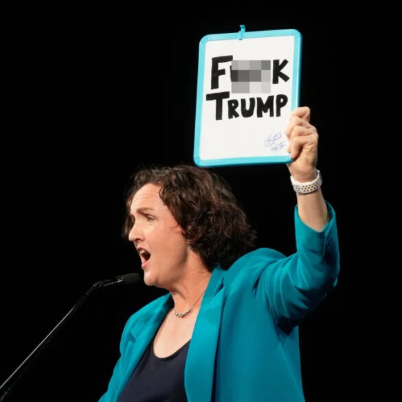 Katie Porter holding up a whiteboard that reads "F*** TRUMP."