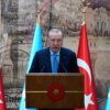 Turkish President Recep Tayyip Erdogan speaking at a podium with Turkish and Somali flags.