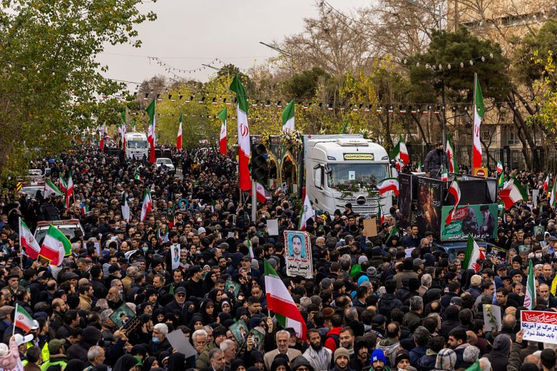 TEHRAN, IRAN - JANUARY 14: A crowd watches as the caskets of members of Iran's security forces, whom authorities said were killed during recent nationwide protests, are transported during a mass funeral on January 14, 2026 outside Tehran University in Tehran, Iran. The country has been gripped by a wave of anti-government protests and the ensuing crackdown, which rights groups say has left thousands of civilians dead. (Photo by Stringer/Getty Images)