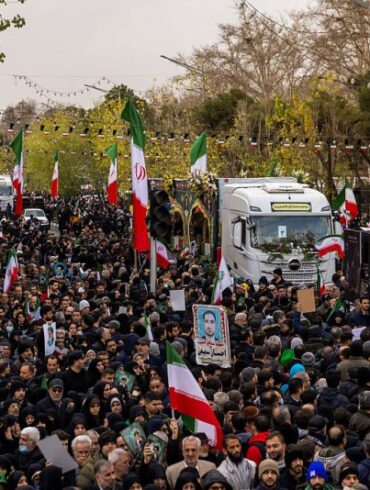 TEHRAN, IRAN - JANUARY 14: A crowd watches as the caskets of members of Iran's security forces, whom authorities said were killed during recent nationwide protests, are transported during a mass funeral on January 14, 2026 outside Tehran University in Tehran, Iran. The country has been gripped by a wave of anti-government protests and the ensuing crackdown, which rights groups say has left thousands of civilians dead. (Photo by Stringer/Getty Images)