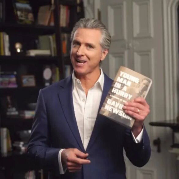 Gavin Newsom holding up his book, "Young Man in a Hurry: A Memoir of Discovery"