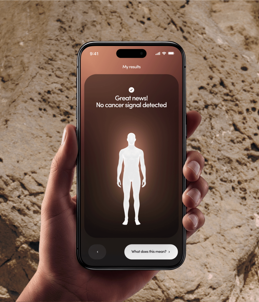 A hand holding a smartphone showing a "no cancer signal detected" result from a blood test.
