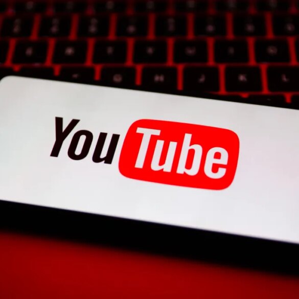 A smartphone displaying the YouTube logo sits on a red backlit keyboard.