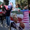 An anti-Iranian regime protestor holds a placard bearing images depicting the son of Iran's Last Shah and now key opposition figure, Reza Pahlavi and US President, Donald Trump as protestors gather in front of the Iranian Embassy in Athens on March 1, 2026, during a protest in support of the US and Israel attack on Iran and the killing of Iran's supreme leader. Iranian state television confirmed the death of Iran's supreme leader Ayatollah Ali Khamenei on February 28, 2026, after US President said he had been killed. The announcement came after the United States and Israel started launching waves of strikes against targets in Iran, sparking swift retaliation by the Islamic Republic. (Photo by Aggelos NAKKAS / AFP via Getty Images)